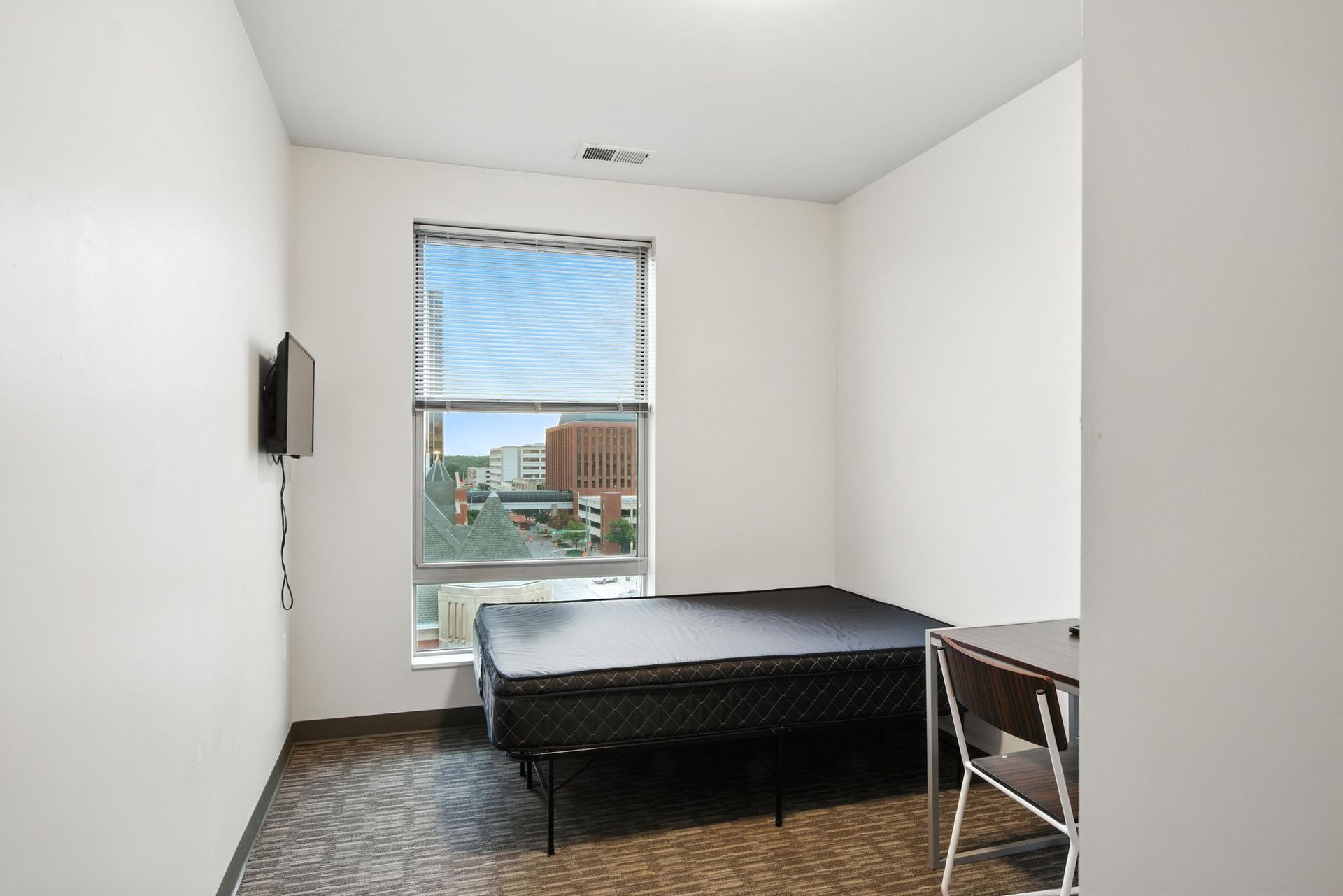 small apartment bedroom with city views through the window